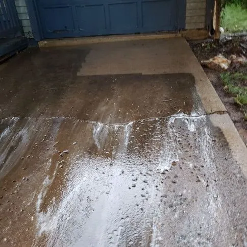 Concrete surface mid-wash with foam and water cascading, half-clean half-dirty