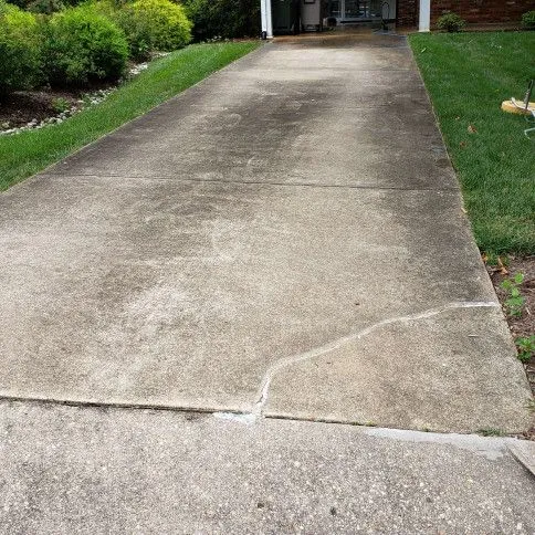 Suburban concrete driveway showing dirt and oil staining before wash